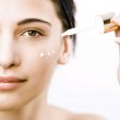 Young woman applying an anti-aging serum on her face with a dropper